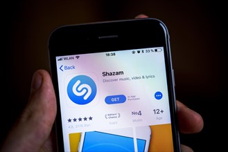 Hand holding iPhone with Shazam App in the Apple App Store