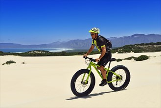 Mountain biker with fat bike in sand dunes