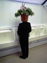 Man with flowerpot on his head in the toilet