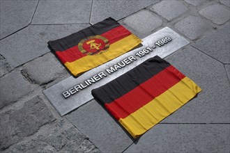 GDR and Germany flag next to the marking of the historical course of the Berlin Wall