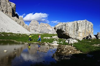 Hikers below the Patern saddle are reflected in a puddle