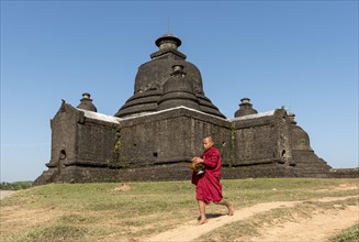 Novice Buddhist monk collects morning alms in front of Laymyetnha Paya