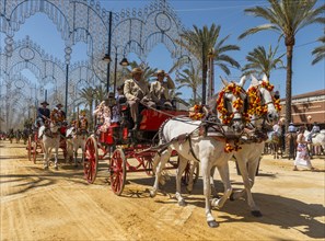 Spaniards in traditional festive dress on decorated horse-drawn carriage