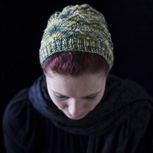 Woman with lowered head and green wool hat