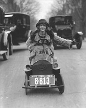 Woman driving in a soapbox on a busy street