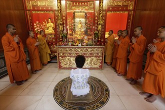 Buddhist Sacrifice Ceremony with praying monks and kneeling woman