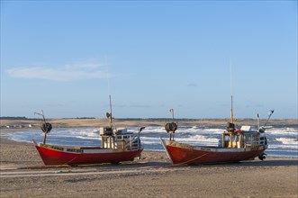 Two red fishing boats lie on the beach of the Atlantic Ocean