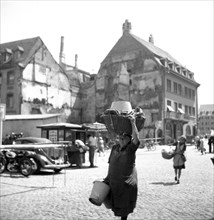 A woman carries a wooden basket on her head