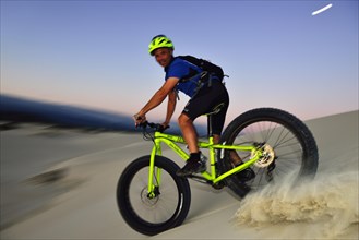 Cyclist with Fatbike descending sand dune