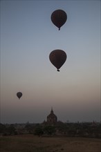 Hot air balloons at sunrise over temples and pagodas