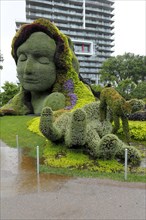 Plant sculpture Mother Earth with modern buildings behind