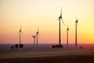 Silhouettes of wind turbines at sunset