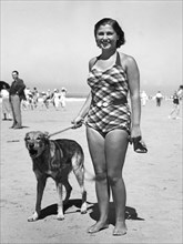 Woman in bathing suit with dog on the beach