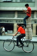 Two Persons and Newspapers on Bike