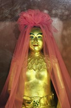 Golden god figure with pink veil