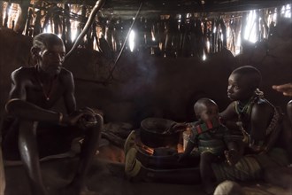 Family sits in mud hut