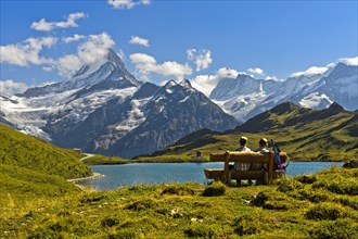 Hikers pausing on a wooden bench at lake Bachalpsee