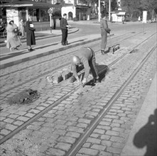 Construction workers paving a road around 1950