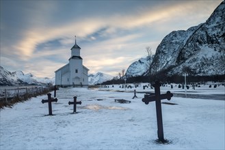 Church with icy cemetery at dusk