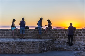 Tourists enjoying sunset at the waterfront of the coastal town Alghero