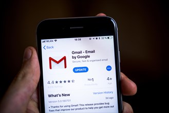 Hand holding iPhone with Google Gmail App in the Apple App Store