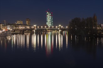 View from the Eiserner Steg over the River Main to the illuminated European Central Bank at night