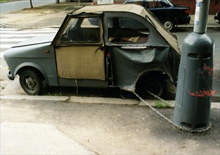 Broken car chained to a lamppost ca. 1970s