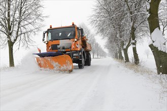 Snow plough on snowy avenue in winter