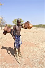 Young Himba man carries food on the cattle drive