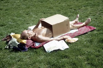 Man sunbathing covered with cardboard piste