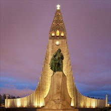 Illuminated Hallgrimskirkja with statue of Leif Eriksson at dusk