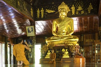 Monks in front of golden Buddha statue
