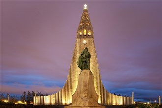 Illuminated Hallgrimskirkja with statue of Leif Eriksson at dusk