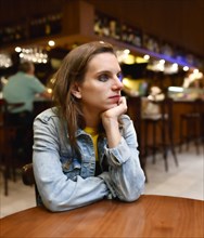 Young woman in a bar looks thoughtful