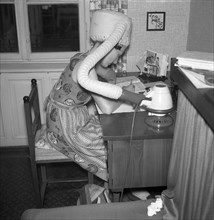 A woman dries her hair at the desk