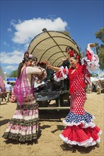 Women wearing colourful gypsy dresses dance the Sevillana