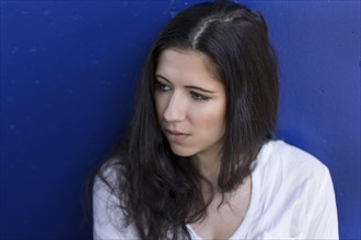 Portrait of a young woman in front of a blue wall