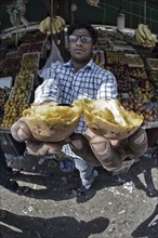 Vendor with vegetable stand offers his goods