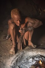 Old Himba chief sitting at the fire in his hut