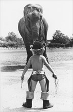 Boy as cowboy in front of elephant