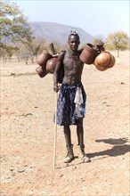 Young Himba man carries food on the cattle drive