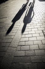 Shadows of pedestrians on pavement