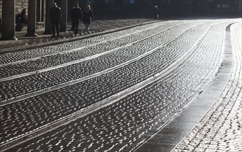 Tram tracks and glittering cobblestones in backlight