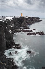 Orange lighthouse Ondverdarnes stands on a dark cliff