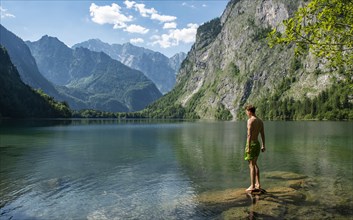 Young man stands on a stone in lake Obersee
