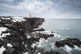 Orange lighthouse Ondverdarnes stands on a dark cliff