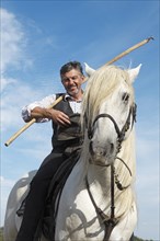 Gardian or traditional bull herder in typical working clothes on a Camargue horse