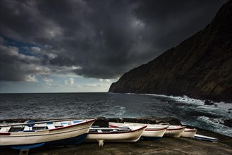 Rowing boats on the shore with dramatic clouds and sea