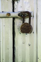Close-up of rusted heavy duty security padlock on silver metal door