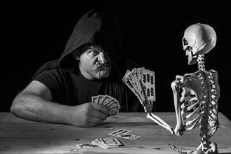 Man plays cards with a skeleton
